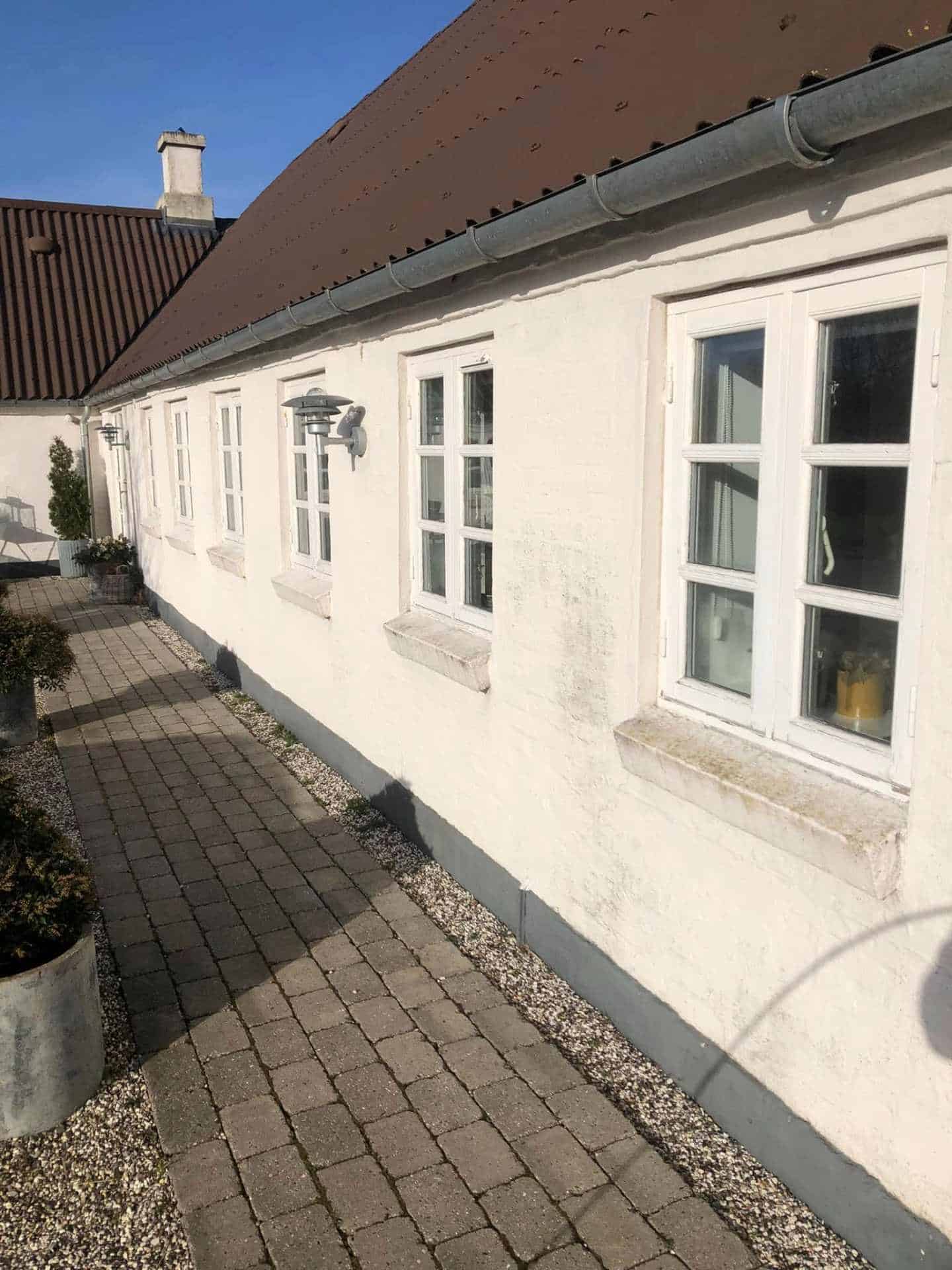Vinkelbygget hvidt hus på landet efter facaderenovering af murer i Åbyhøj