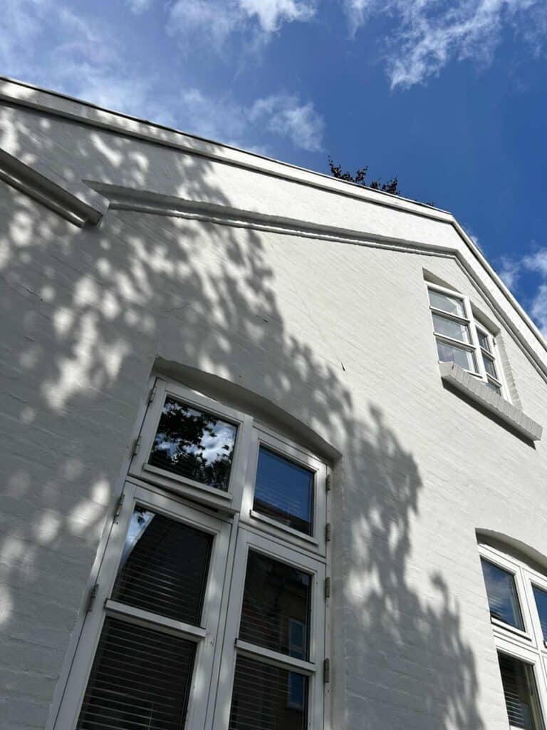 Hvidpudset gavl og udhæng på hus efter facaderenovering Ry