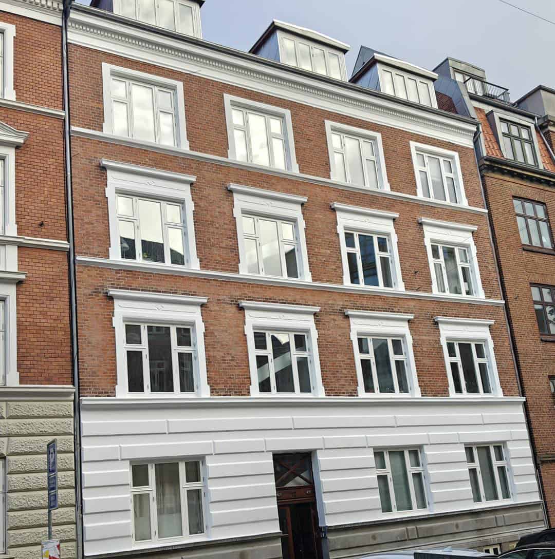 Rød etageejendom i bymiljø efter omfattende facaderenovering Århus