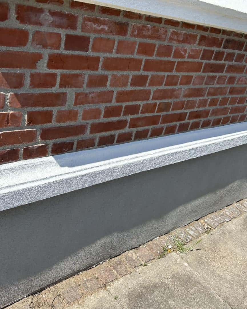 Rød murstensvæg og hvid underkant efter reparation af sokkel